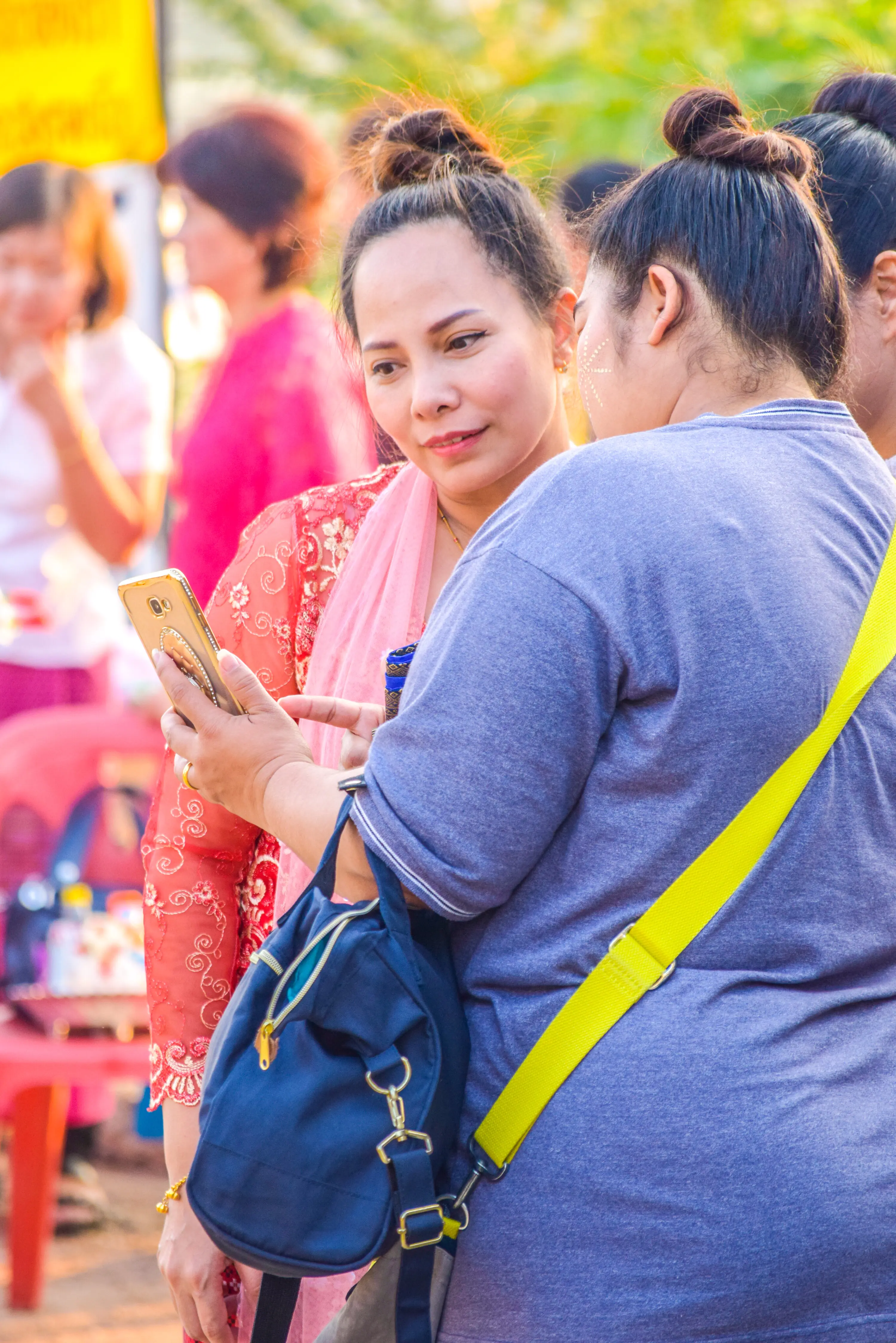 Eine Frau zeigt ihren Freundinnen ein Handy, während sie im Freien stehen.